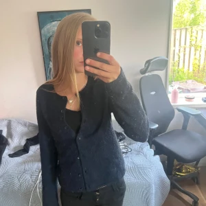 Svart kofta från Gina  - Säljer en svart kofta från gina . Koftan har rund halsringning, långa ärmar och knäppning framtill med svarta knappar. Den är mjuk och passar perfekt till lager-på-lager-stil.