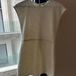 Vit ärmlös klänning i stickat material - Säljer en enkel och stilren vit klänning i stickat material. Klänningen är ärmlös och har en rak passform med rund halsringning. Perfekt för dig som gillar minimalistisk stil.