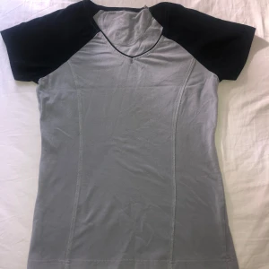 Grå t-shirt med svarta ärmar - Sportig grå t-shirt med svarta korta ärmar och kontrastsömmar. 