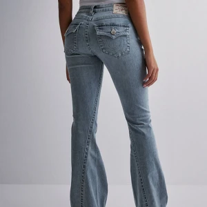 Joey low rise flare jeans från True Religion - Säljer ett par ljusblå lågmidjade jeans från True Religion med bootcut-passform (modellen Joey Low Rise Flare) i storlek W28! Fint skick men något slitna längst ner. Skulle säga att de passar S perfekt, stretchiga! 🥰