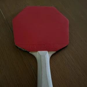 STIGA Table Tennis Racket - En snygg och välbevarad bordtennisracket från STIGA med röd och svart gummiyta. Perfekt för dig som vill ta ditt spel till nästa nivå, oavsett om du är nybörjare eller mer erfaren. Greppet är bekvämt och racketen har en klassisk design.