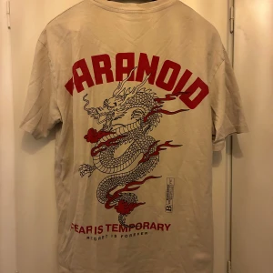 Beige t-shirt med tryck - Beige t-shirt med stort rött drakmotiv på ryggen. Strl S (oversized)