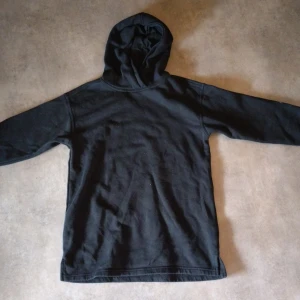 Svart hoodie - En klassisk svart hoodie med lång ärm och huva. Perfekt för en avslappnad stil och enkel att matcha med det mesta. Mjuk och bekväm, passar både till jeans och mjukisbyxor.