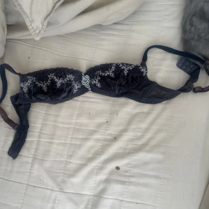 Svart spets-bh med broderi - Säljer en svart bh med vacker spets och vitt broderi på kuporna. Bh:n har justerbara axelband och hakknäppning bak. Perfekt för dig som vill ha något snyggt och bekvämt under kläderna. Stl 80A