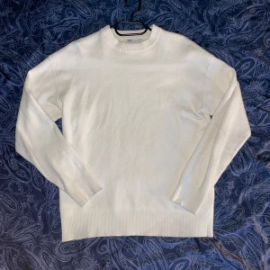 Stickad tröja från Zara - Säljer en stilren vit stickad tröja från Zara. Tröjan har rund halsringning, långa ärmar och breda ribbade muddar vid ärmslut och nederkant. Materialet är stickat superior ( väldigt lent och skönt! Nästan som Kashmir!