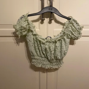 Ljusgrön spetts  topp från Gina Tricot - Superfin ljusgrön croppad topp från Gina Tricot med spetts material och puffiga korta ärmar. Toppen har resår vid midjan och ärmarna för en söt och somrig look. Perfekt till varma dagar! I strl s