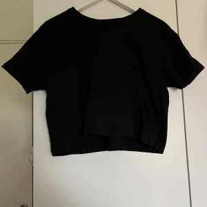 Svart croppad t-shirt - En enkel svart croppad t-shirt med korta ärmar. Perfekt till jeans eller kjol för en avslappnad stil. T-shirten har en rak passform och är tillverkad i ett mjukt material. Säljer samma på vinted så kontakta gärna innan ni trycker på ”köp”! 