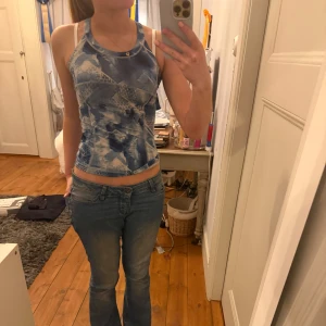 Blå mönstrad träningstopp med korsade band - Säljer en blå träningstopp med abstrakt mönster och smala axelband som korsas i ryggen. Toppen har en tight passform och är perfekt för sommaren. Snygg och unik design! Liten storlek men passar mig som brukar vara S!🌸