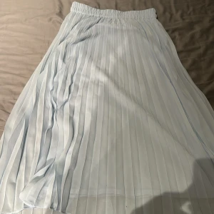 Ljusblå kjol från Monki - Säljer en ljusblå kjol från Monki med resår i midjan. Kjolen är lång och har ett luftigt, flowy tyg. Perfekt för dig som gillar en stilren och fräsch look.