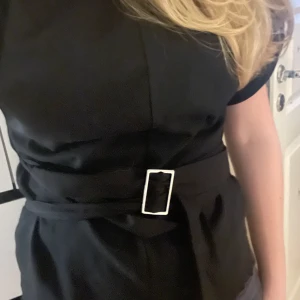 Svart topp med bälte - Säljer denna superfina toppen från Zara som är mycket sparsamt använd!  Den har ett matchande tygbälte med silverfärgat spänne i midjan som ger en snygg siluett. Enkel och stilren design som passar till många tillfällen. 💗