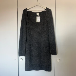 Mörkgrå stickad klänning  - Mysig mörkgrå stickad klänning med lång ärm och unik asymmetrisk halsringning. Perfekt för kyligare dagar och enkel att styla med boots eller sneakers. Den är helt ny och lappen är fortfarande kvar, säljer då den inte har kommit till användning✨🫧💕
