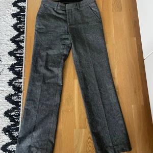 Grå kostymbyxor från Batistini - Snygga grå kostymbyxor från Batistini i ullblandning. Byxorna har klassisk passform med raka ben och hällor för bälte. Sitter som en storlek 36/38