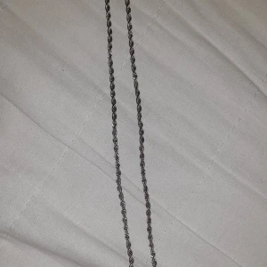 Silverfärgat tvinnat halsband - Säljer ett stilrent halsband i silverfärg med tvinnad kedja. Perfekt för dig som gillar enkla men snygga accessoarer. Passar till många olika stilar och är lätt att matcha med andra smycken.