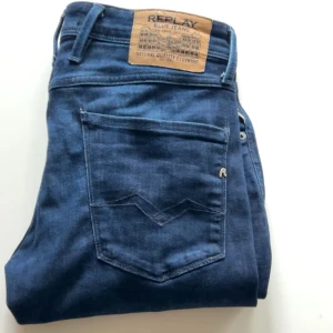 Replay Anbass slim fit jeans blå - Säljer ett par blå Replay Anbass jeans i slim fit med klassisk femficksdesign och dragkedja. Jeansen har snygga detaljer och är tillverkade i ett stretchigt material för extra komfort. Midjemått W31 och längd L34.