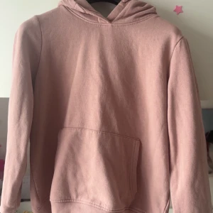 Rosa hoodie med ficka - Mysig rosa hoodie med huva och stor magficka framtill. Perfekt för en avslappnad stil och enkel att matcha med jeans eller mjukisbyxor.