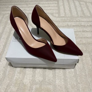 Vinröda pumps med spetsig tå - Säljer ett par eleganta vinröda pumps med spetsig tå och smal klack. Skorna har en stilren design och är perfekta för att lyfta vilken outfit som helst. Storlek 38.