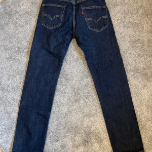 Mörkblå Levi's 502 jeans - Säljer ett par mörkblå Levi's 502 jeans med klassiska bakfickor och gul söm. Jeansen har rak passform och är tillverkade i jeansmaterial. De är nästan som nya. Strl: W29 L32