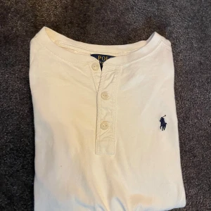 Ralph Lauren tröja - Klassisk vit långärmad tröja från Polo Ralph Lauren med knappar vid halsen och broderad logga på bröstet. Perfekt för sommaren. Tillverkad i mjuk bomull för extra komfort. Är upp för förhandling. Ifall du har någon beundran, hesitera inte att fråga.