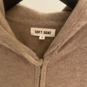 Soft Goat - Säljer denna beige hoodie i kashmir från Soft Goat. Tröjan har dragkedja framtill, huva och två fickor. Perfekt för kyliga dagar och enkel att matcha med det mesta. Klassisk och stilren design. Skick 8/10, finns ett jättelitet hål man inte  ser (bild 2) storlek S men sitter ganska litet