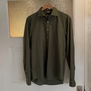 Olivgrön skjorta från Stenströms - Snygg olivgrön skjorta från Stenströms med klassisk krage och knäppning framtill. Skjortan har långa ärmar och är tillverkad i ett mjukt material som känns bekvämt mot huden. Aldrig använd heller även fast mitt pris är betydligt mycket lägre än retailpriset.