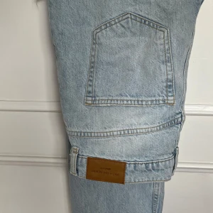 Ljusblå jeansbyxor från Gina  - Säljer ett par ljusblå jeansbyxor från Gina med slitningar på båda benen.