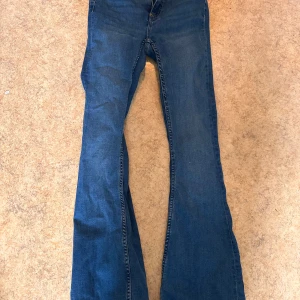 Blå bootcut jeans  - Säljer ett par klassiska blå bootcut jeans med normal passform. Jeansen har fem fickor och stängs med dragkedja och knapp. Perfekta för dig som gillar en retroinspirerad look med utsvängda ben.