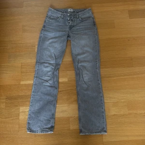 Grå jeans från Lager 157 - Säljer ett par grå jeans från Lager 157. Byxorna har normal passform, raka ben och knappgylf. Perfekta för dig som gillar en enkel och stilren look. Jeansmaterialet är mjukt och bekvämt. Lite slitningar högst upp och längst ner på jeansen.