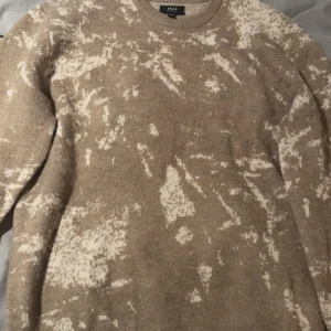 Beige och vit stickad tröja  - Säljer en beige stickad tröja med vitt abstrakt mönster. Tröjan har rund halsringning och långa ärmar. Perfekt för kyligare dagar och enkel att matcha med jeans eller kostymbyxor. 