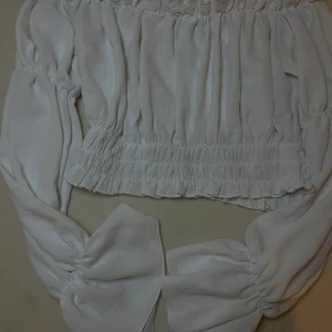 Vit offshoulder blus🤍 - Säljer en söt vit offshoulder blus i storlek XS. Blusen har långa volangärmar och smockdetaljer vid midjan och axlarna för en snygg passform. Perfekt för vår och sommar, lätt och luftig i materialet. Pris kan såklart diskuteras och andra frågor!🤍