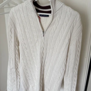 Vit stickad tröja med dragkedja från Felix Hardy - Säljer en helt ny (taggen kvar!) kabelstickad halfzip från Felix Hardy – superfräsch i vit med snygga bruna detaljer i kragen. Perfekt för kyliga sommarkvällar, men också en favorit till både höst och vår. Den här modellen är helt slutsåld överallt och riktigt svår att få tag på – så vill du sticka ut och ha något ingen annan har? Passa på! Skicka DM för pris eller frågor. Först till kvarn! 🪭🪩✨