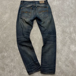 Nudie Grim Tim - Tja! Säljer dessa sjukt snygga blå Nudie ”Grim Tim” jeansen med den fetaste tvätten nånsin! Size 31/32, mått: 40cm midja, 105cm ytterbenslängd. Skriv vid funderingar!