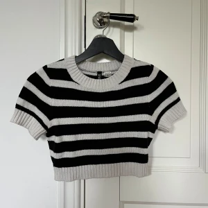 Svart och vit randig croppad stickad tröja - Säljer en croppad stickad tröja från H&M med svarta och vita ränder. Tröjan har korta ärmar och ribbade kanter vid hals, ärmslut och nederkant. Perfekt för en trendig och avslappnad stil.