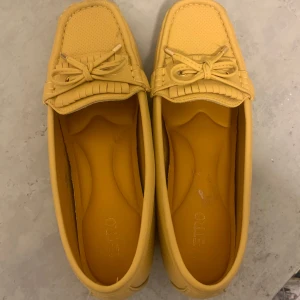 Yellow Loafers - Stylish yellow loafers with a decorative bow at the front and a perforated pattern on the upper. The shoes have a classic round toe and comfy sole, perfect for a stylish look.