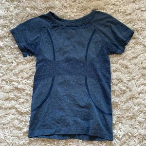 Blå sportig t-shirt - Snygg blå t-shirt med korta ärmar och sportigt, diskret mönster i olika blå nyanser. T-shirten har rund halsringning och är tillverkad i ett stretchigt material som passar perfekt för träning eller en aktiv vardag.