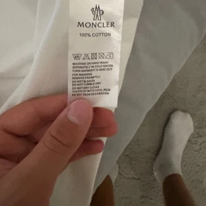 Vit Moncler t-shirt  - Clean vit t-shirt från Moncler i 100% bomull med klassisk rund hals och korta ärmar. På bröstet sitter Monclers ikoniska logga broderad. Perfekt basic med exklusiv känsla och snygg passform.