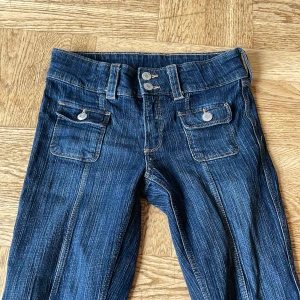 Blå bootcut jeans med fickor - Säljer ett par mörkblå jeans också köpta från plick. De har två fickor där fram men inga där bak.   Köpte dem för 700kr (frakt inkluderat) där av priset, men det kan diskuteras. De är i barnstorlek 158 men kan även passa de som är lite över 160-165. Använda ett få tal gånger.
