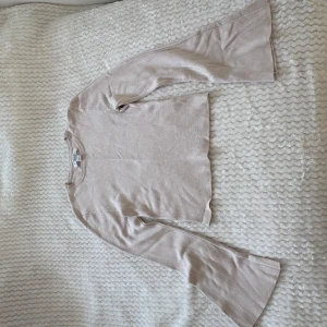 Beige croppad tröja med utsvängda ärmar - Säljer en beige croppad tröja från new yorker, med långa utsvängda ärmar. Tröjan har en enkel design och är tillverkad i mjukt material som känns skönt mot huden. Perfekt för dig som gillar en stilren och trendig look.