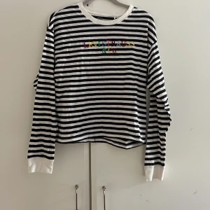 Randig Levi’s tröja - En svart och vitrandig långärmad t-shirt från Levi’s med broderad text i regnbågens färger! Jätteskönt material!!