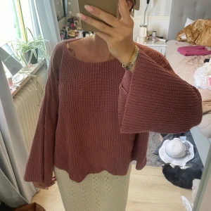 Rosa stickad tröja med vida ärmar - Mysig stickad tröja i en dämpad rosa nyans med breda, vida ärmar och avslappnad passform. Tröjan har rund halsringning och är perfekt för lager-på-lager. Passar dig som gillar en chill och trendig look.