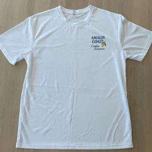 Costa Serena XLJ Beach Club Amalfi Coast - Amalfi Coast Special Edition XLJ Beach Club – för dig som rör dig mellan italienska klippor och svenska skärgårdar. Tidlös vit med diskret tryck. Bärs bäst med solglasögon och självsäkerhet.