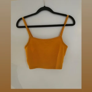 Gul ribbad croppad linnetopp - Snygg gul croppad linnetopp med smala axelband och ribbad struktur. Perfekt för varma dagar och enkel att matcha med jeans eller kjol. Fräsch och trendig färg som verkligen poppar.