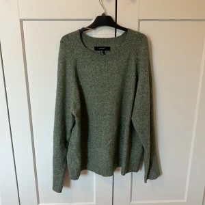 Grön stickad tröja från Veromoda  - Mysig grön stickad tröja från Vero Moda med rund halsringning och långa ärmar. Tröjan har en enkel och stilren design med ribbade muddar vid ärmslut och nederkant. Perfekt för lager-på-lager under kyliga dagar. Väldigt mjuk.