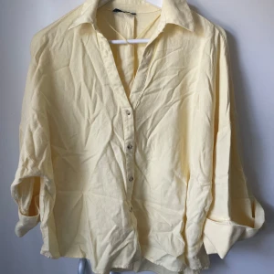 Ljusgul skjorta från Zara - Ljusgul skjorta från Zara i bomull med klassisk krage och knappar framtill. Skjortan har lång ärm med breda manschetter och en avslappnad, loose passform. Perfekt för dig som gillar en enkel men fräsch stil.