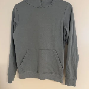 Grå hoodie från OTP Leisurewear XS - En stilren grå hoodie från OTP Leisurewear i storlek XS. Tröjan har en klassisk huva, känguruficka framtill och ribbade muddar vid ärmslut och nederkant. Perfekt för chill dagar eller när du vill ha en enkel och snygg look.