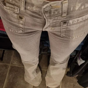 Snyggaste grå y2k lowrise flare  - Snyggaste grå y2k lowrise flare jeansen! Fina detaljer med knäpplock på fickor både fram och bak. Midjemått ca 33 CM. Innerbenslängd ca 80 CM. Absolut nyskick. 