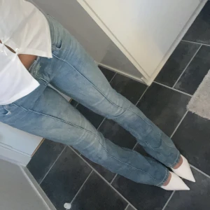 Bershka Ljusblå bootcut jeans med sömdetaljer - Säljer ett par ljusblå jeans med bootcut-modell och markerade sömmar längs benen. Jeansen har låg midja och klassisk femficksdesign. Materialet är denim och passformen är slim upptill med utsvängda ben. Perfekta för dig som gillar en retro vibe.
