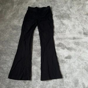 Svarta bootcut-byxor från Vero Moda - Säljer ett par svarta bootcut-byxor från Vero Moda i storlek S/36T. Byxorna har hög midja och är tillverkade i ett stretchigt, mjukt material som sitter snyggt och bekvämt. Perfekta för dig som gillar en klassisk och stilren look.