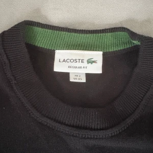 Svart stickad tröja från Lacoste XS - Svart stickad tröja från Lacoste i regular fit, använd 3-5 gånger, mycket skönt matrial med stretch, Nypris (1600kr)