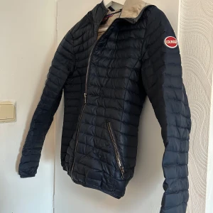 Mörkblå Colmar dunjacka 12Y - Snygg mörkblå dunjacka från Colmar med quiltad design och dragkedja framtill. Jackan har lång ärm, två dragkedjefickor och ljusbeige insida. Perfekt för kyliga dagar och riktigt lätt att bära. Pris går att diskutera ❤️
