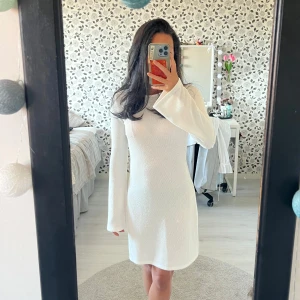 Vit strandkortklänning med utsvängda ärmar - Säljer denna supersöta vita strandkortklänningen med långa utsvängda ärmar. Baksidan har djup urringning med knytband i nacken. Klänningen är figurnära och har en clean, stilren look. Använd endast ett fåtal gånger och har inga defekter! Vid intresse eller frågor, skriv privat💕 